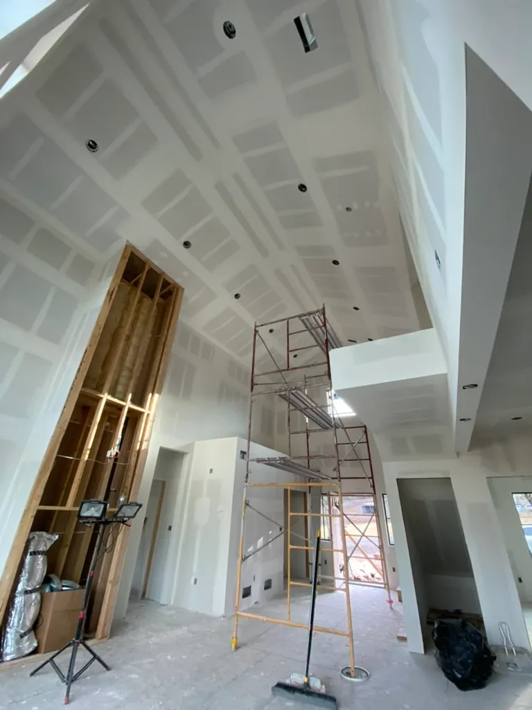 Two-story vaulted room taped, with scaffolding